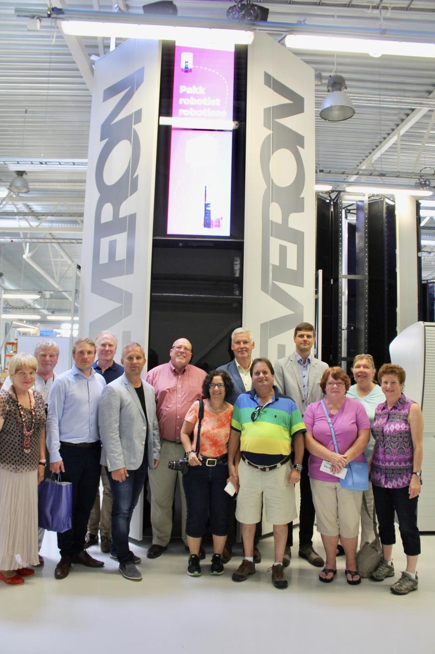 Visitors in Cleveron's factory posing in front of the Cleveron 401 parcel robot