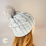 Light grey knit winter hat with grey faux fur pom on model