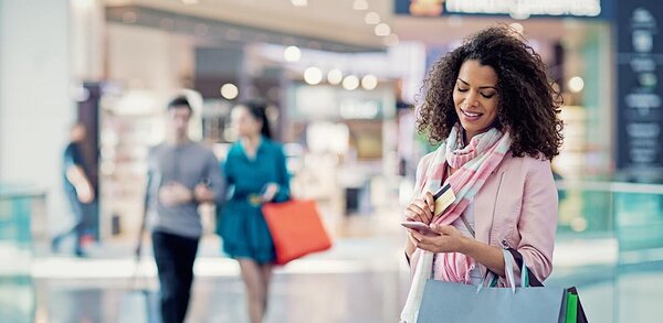 Woman in a pink jacket using a credit card via smartphone