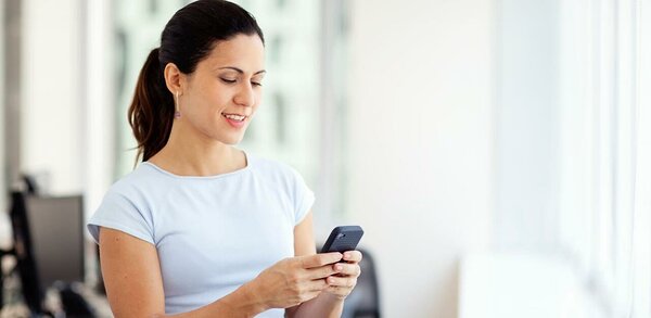 Woman in white shirt reading text message on mobile phone