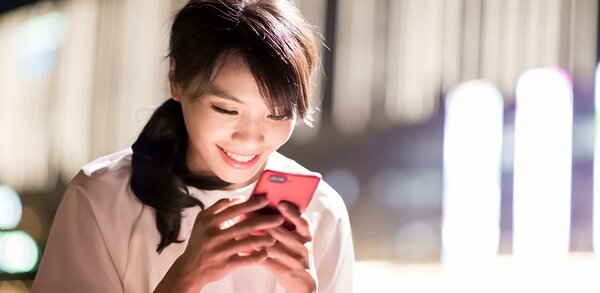 Asian woman looking at her pink smartphone