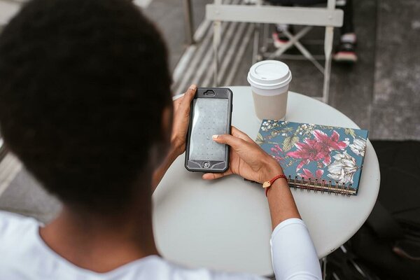 Black woman messaging at a cafe