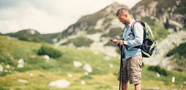 Hiker receiving a text alert in mountains