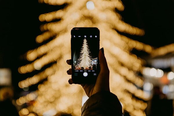 Woman taking a photo of a golden Christmas tree