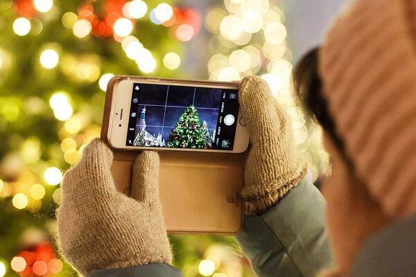 Person photographing a Christmas tree using a smartphone