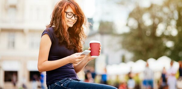 Woman checking texts on a smartphone while drinking coffee