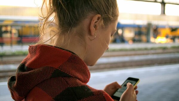 Woman in a red hoodie reading texts in a train station