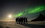 A group of aurora hunters greeting the auroras with the full moon in the sky