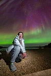 A happy aurora hunter with strong northern lights in the sky in Rovaniemi Finland