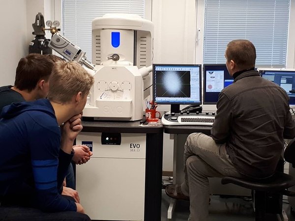 TTÜ proffessor Olle Hints noortele skanneerivat elektronmikroskoopi tutvustamas.