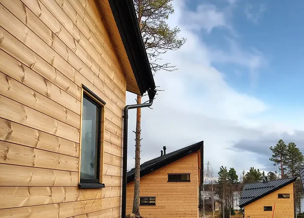 Two-story glass wall showcasing serene Pyhäjärvi lake and fells at dawn