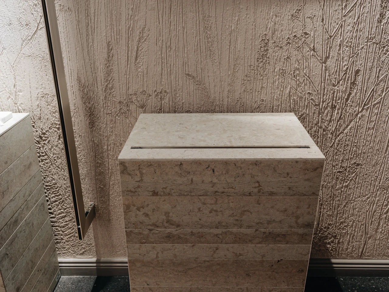 Lubjakivist postamendi taga olev lubimarmorinoga kaetud sein on püütud sarnase toonigammaga lahendada.