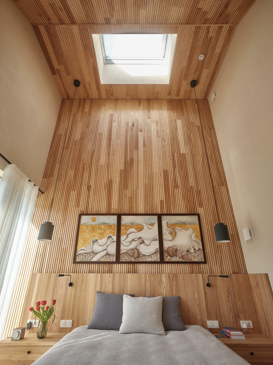 Magamistoa kõrgustesse ulatuvatele puitpaneelidele pakuvad mahedat tasakaalu naturaalvalge savikrohviga viimistletud pinnad.