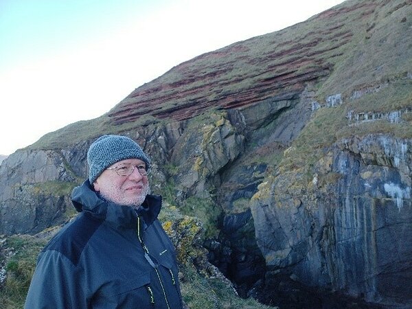 Heikki Bauert stands in front of the rock face; the world-famous unconformity between Silurian and Devonian Old Red sandstone layers is visible right above Heikki's head (photo: Ville Järvinen)