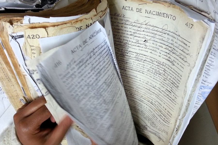 Registres historiques dominicains de naissance provenant d'archives montrant des documents vieillis nécessitant une recherche experte