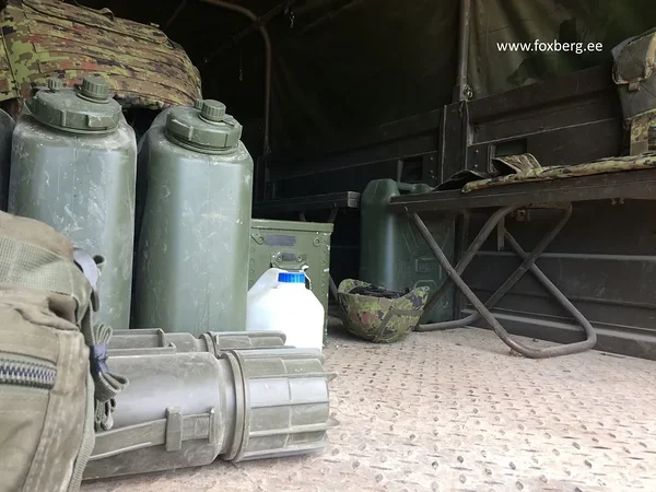 Jerricans à eau militaires Scepter dans la benne d'un camion avec équipement de campagne, casque et tubes à munitions