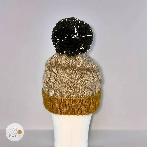 Hand-knitted acrylic reflective bobble hat in mustard yellow, beige, and dark green. 