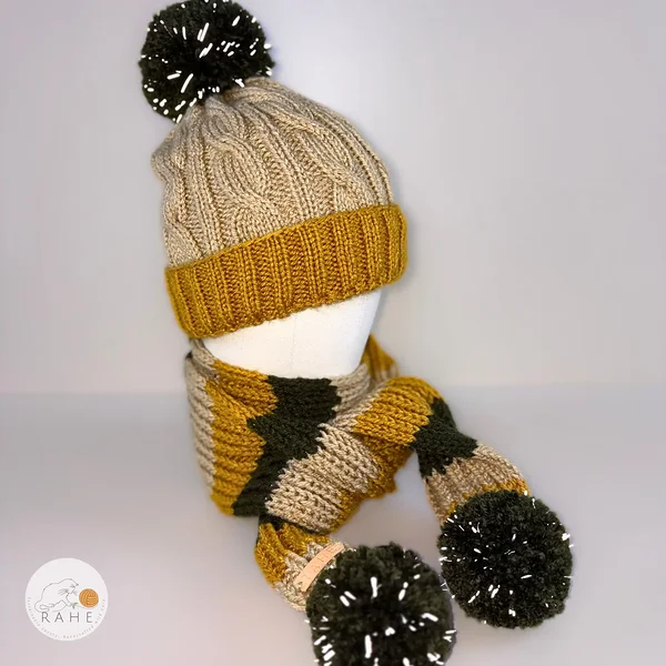 Shop handmade gifts. Hand-knitted winter beanie with a large reflective pom pom. Long striped pom pom scarf in mustard yellow, dark green, and beige.