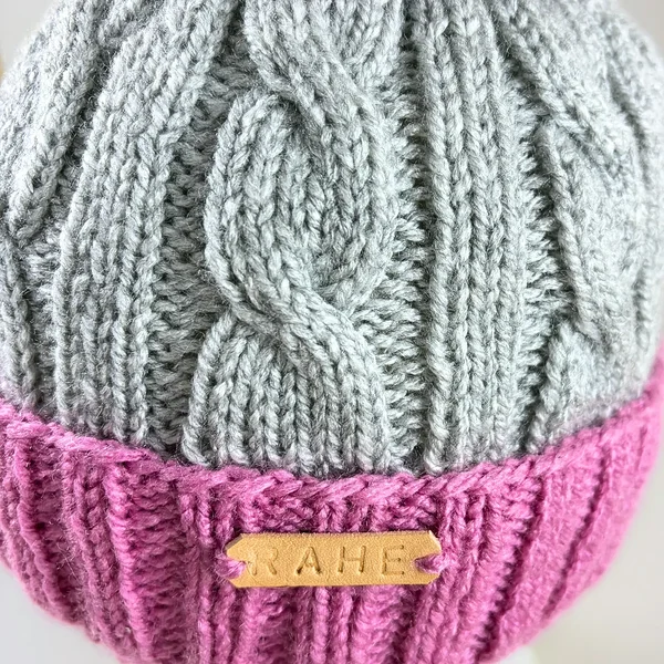 Cable knit ski holiday hats. Hand-knitted reflective pom pom hats in grey, pink, and purple. Estonian handicraft slow fashion gifts.