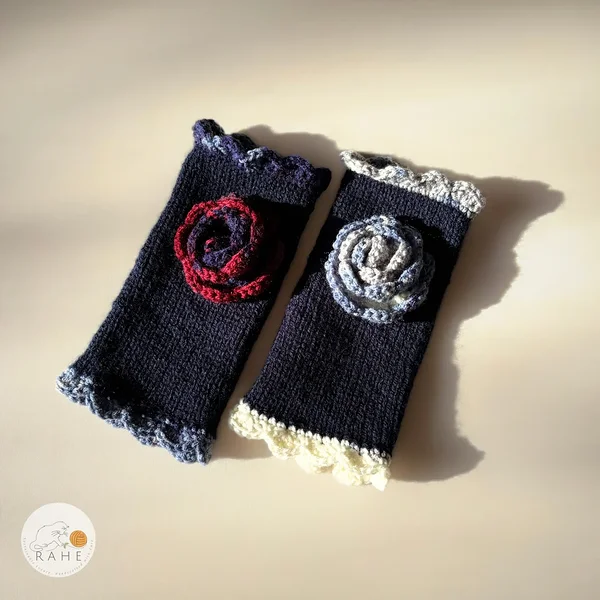 Hand-knitted navy blue fingerless gloves with lace edging and a crocheted flower – classic Nordic handmade design with contrasting details.