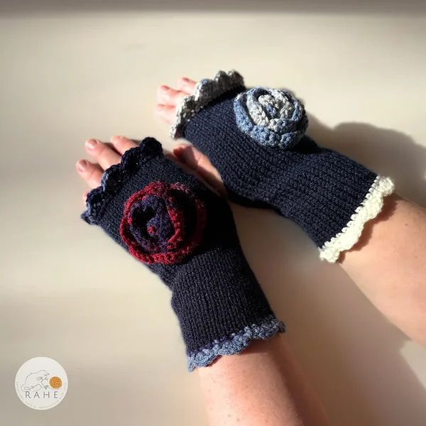 Hand-knitted navy blue fingerless gloves with lace edging and a crocheted flower, worn on a model – classic Nordic handmade design in elegant contrasting colours.