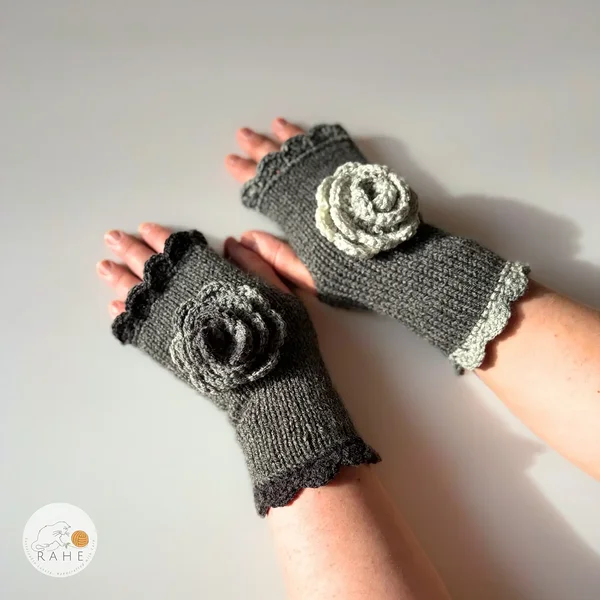 RAHEcraft hand-knitted fingerless gloves in grey with charcoal and light grey lace edging and a crocheted flower. The smooth knit keeps wrists warm while leaving fingers free for everyday use.