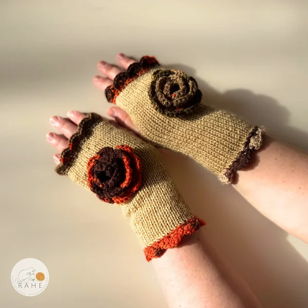 RAHEcraft hand-knitted fingerless gloves in beige with orange and brown lace edging and a crocheted flower. The smooth knit keeps wrists warm while leaving fingers free for everyday use.