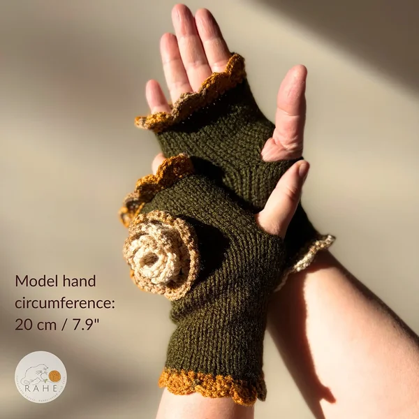 RAHEcraft hand-knitted fingerless glove in olive green with mustard yellow and beige lace edging and a crocheted flower. The image shows the fit of the glove on a model with a hand circumference of 20 cm (7.9").