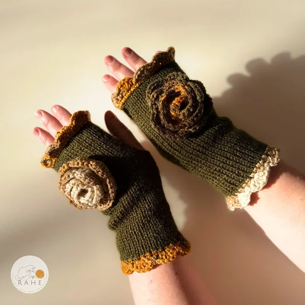 Close-up of RAHEcraft hand-knitted fingerless gloves in olive green. The textured crochet flower and mustard yellow lace edging create a romantic and feminine look.