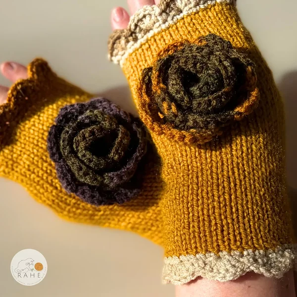 Hand-knitted mustard yellow fingerless gloves with cream lace edging and a crocheted flower, highlighting the rich texture and warm Nordic autumn colour palette.