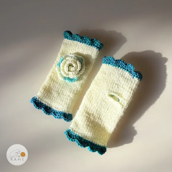 RAHEcraft hand-knitted fingerless gloves in ivory white with deep teal lace edging and a crocheted flower. The smooth knit keeps wrists warm and adds a romantic handmade touch.