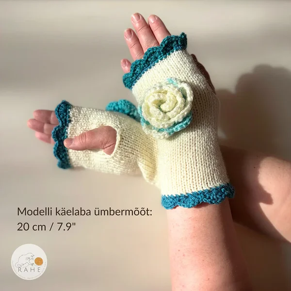 RAHEcraft käsitsi kootud sõrmedeta kinnas looduslikvalges toonis petroolsinise pitsilise ääre ja heegeldatud lillega. Pildil on näha kinnaste istuvus – modelli käelaba ümbermõõt on 20 cm (7.9").