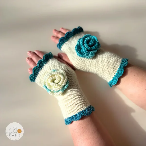RAHEcraft hand-knitted fingerless gloves in ivory white with deep teal lace edging and a crocheted flower. The smooth knit keeps wrists warm while leaving fingers free for everyday use.