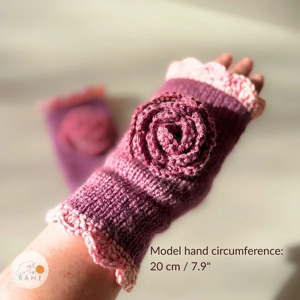 RAHEcraft hand-knitted fingerless glove in berry pink with soft pink lace edging and a crocheted flower. The image shows the fit of the glove on a model with a hand circumference of 20 cm (7.9").