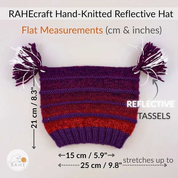 RAHEcraft hand-knitted reflective beanie shown flat with measurements, featuring purple and red gradient striped wool blend knit, ribbed cuff, and reflective tassels for visibility. Soft, stretchy winter hat designed to fit kids, teens, and adults, handma
