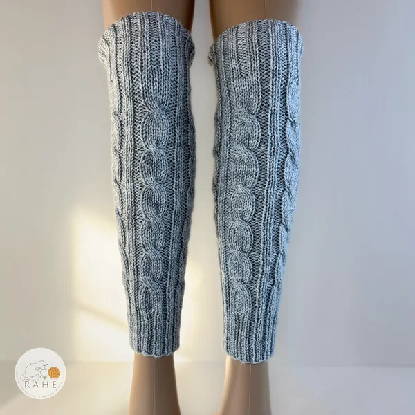 RAHEcraft hand-knitted cable knit leg warmers worn on legs, showing the elegant cable pattern and ribbed cuffs. Warm winter accessory available in Adult, Teen and Kid sizes.