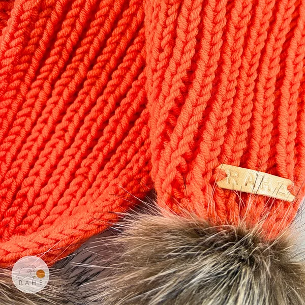 Close-up of the knit texture and RAHEcraft label on an orange merino wool scarf