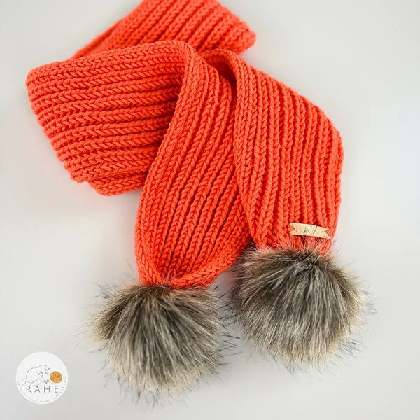 Orange hand-knitted merino wool scarf with a faux fur pom-pom, laid flat