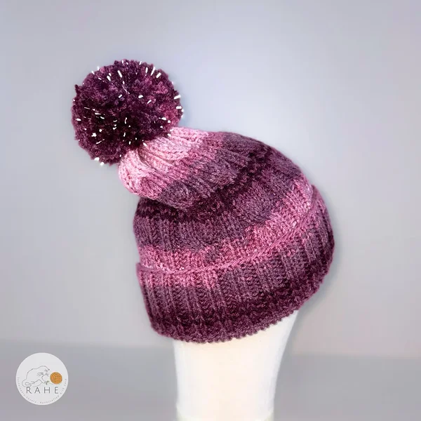 Handcrafted winter beanie with a reflective pom. Pink and purple gradient winter hat for kids, teens, and adults. Handmade in Europe, in Estonia.