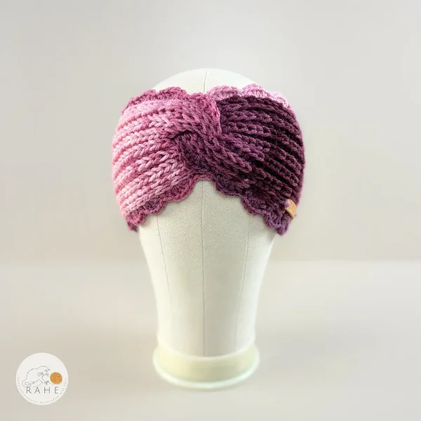 Hand-knitted wide acrylic headband in gradient white, pink, and purple, fisherman’s knit pattern with hand-crocheted scalloped edge, front view on mannequin, RAHEcraft
