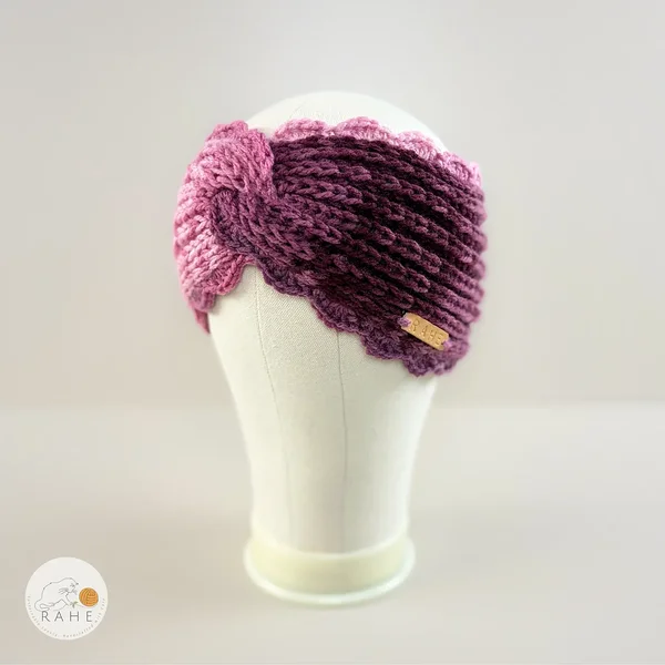 Hand-knitted wide acrylic headband in gradient white, pink, and purple, fisherman’s knit with hand-crocheted scalloped edge and RAHE label, side view, RAHEcraft