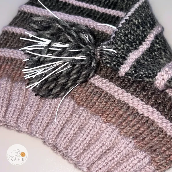 Detail view of a RAHEcraft hand-knitted reflective knit hat for kids and adults, highlighting reflective tassels and soft ribbed wool texture.