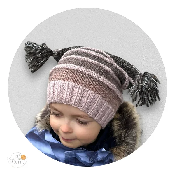 RAHEcraft hand-knitted reflective hat worn by a child, featuring a soft ribbed brim, striped knit design, and reflective tassels for visibility during darker seasons.