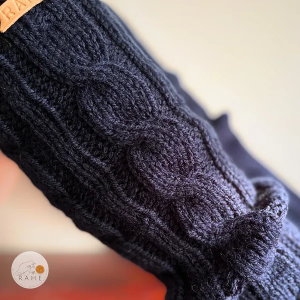 Close-up of RAHEcraft hand-knitted cable knit leg warmers in soft dark blue yarn. The detailed knit texture shows the classic cable pattern. Available in three sizes: Teen and Kid.