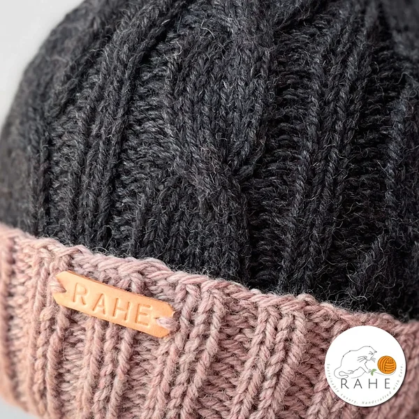 Close-up of charcoal and beige-pink cable knit wool hat – handmade winter beanie for women and men by RAHEcraft, made in Estonia.
