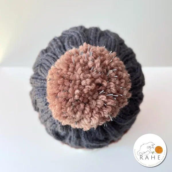 Top view of handmade charcoal and beige-pink cable knit hat with reflective pom-pom – repurposed wool beanie for men and kids, Estonian handicraft by RAHEcraft.