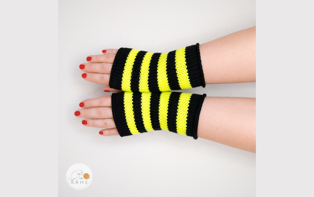 Hand-knitted merino wool arm warmers with black and neon yellow stripes, shown on straightened hands. RAHEcraft.