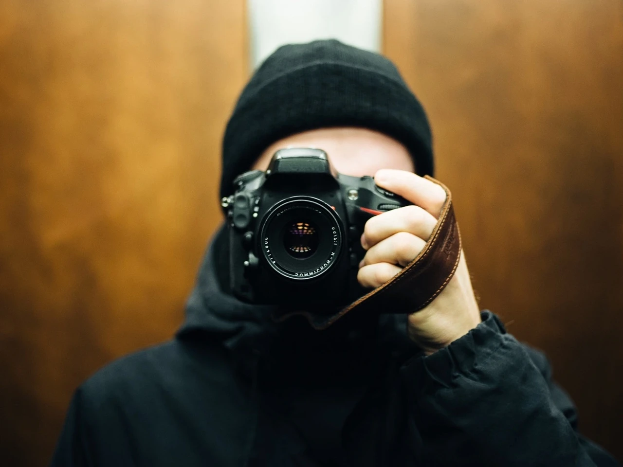 A photographer holding a camera fitted with a Stella Soomlais leather wrist strap